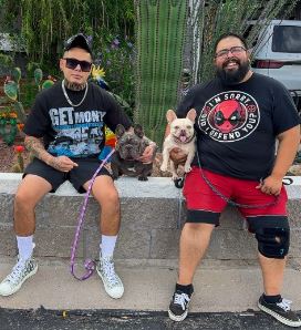 Two Arizona Frenchie breeders seated with a lilac and a blue French Bulldog near desert cacti.